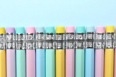 Açık mavi arkaplanda silgileri olan çizgili kalemler, düz yatış