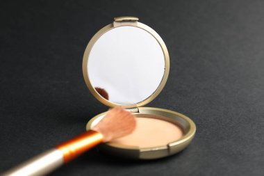 Aynalı yüz pudrasını aç ve siyah arkaplanda fırçala, kapat