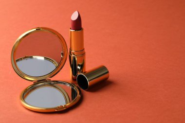 Açık cep aynası ve mercan arka planda ruj, yakın plan. Metin için boşluk