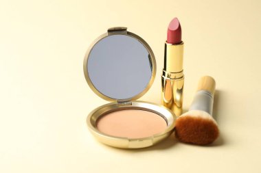 Aynalı yüz pudrası, ruj ve bej arka planda fırça, yakın plan
