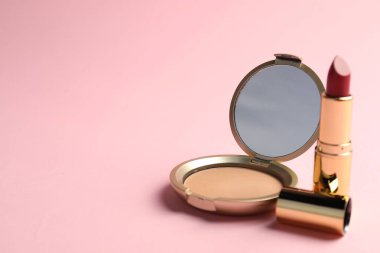 Aynalı açık yüz pudrası ve pembe arka planda ruj, yakın plan. Metin için boşluk