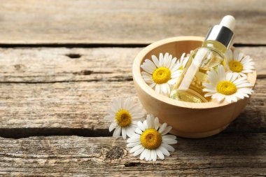 Ahşap masada bir şişe yağ ve papatya çiçeği, yakın plan. Metin için boşluk