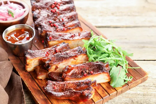 Lezzetli pirzola, sos ve roka ahşap masada, yakın plan.