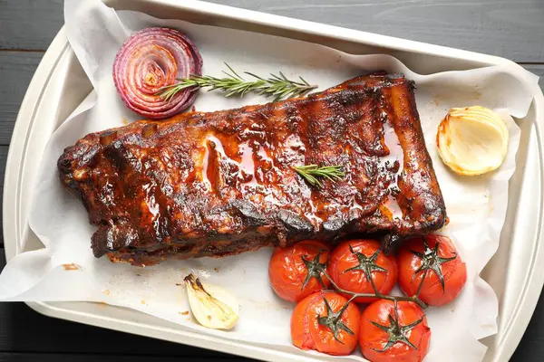 Lezzetli kaburgalar, biberiye, fırında soğan ve gri ahşap masa üzerinde kurutulmuş domatesler.