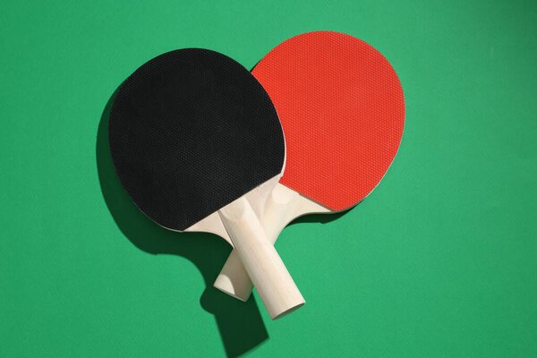 Ping pong rackets on green background, top view
