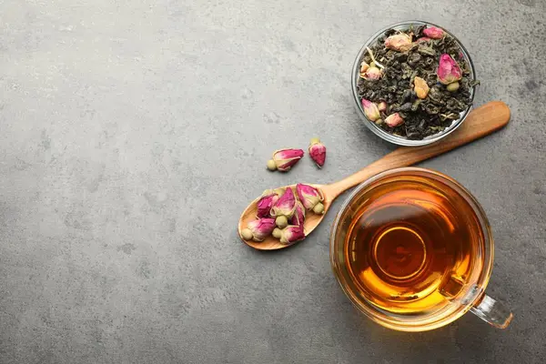 Aromatik bitki çayı, kuru yapraklar ve gri masadaki çiçekler, düz yatak. Metin için boşluk
