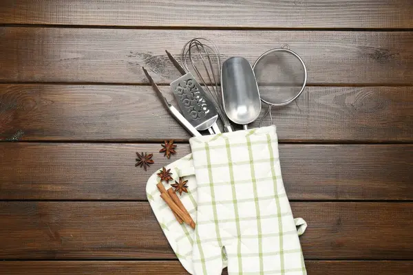 Farklı mutfak aletleri fırın eldiveni, tarçın ve anason yıldızları ahşap masa, düz yatıyordu.