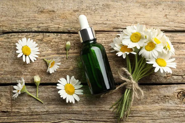 Bir şişe yağ ve papatya çiçekleri ahşap masa üzerinde, düz yatıyordu.
