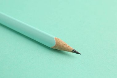 Turkuaz arka planda bir grafit kalem, yakın plan.