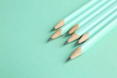 Turkuaz arka planda birçok grafit kalem, yakın plan. Metin için boşluk