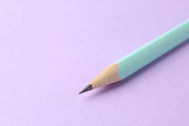 Mor arka planda bir grafit kalem, yakın plan. Metin için boşluk