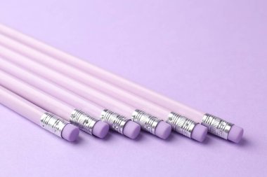 Menekşe arka planında silgi olan birçok grafit kalem, yakın plan. Metin için boşluk