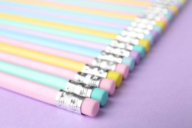 Menekşe arka planında silgi olan birçok grafit kalem, yakın plan. Metin için boşluk