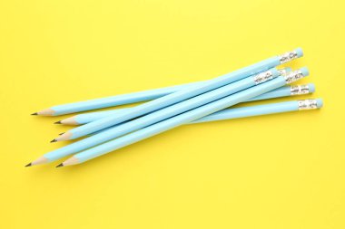 Sarı arka planda silgisi olan bir sürü grafit kalem, düz yatıyordu.