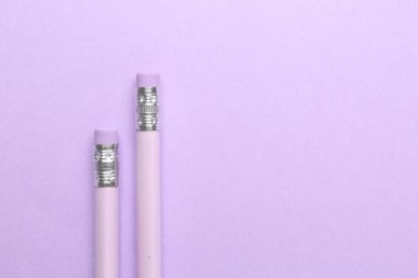 Menekşe arkaplanda silgisi olan iki grafit kalem, düz. Metin için boşluk