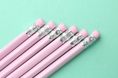 Turkuaz arka planda silgileri olan birçok grafit kalem, düz konum