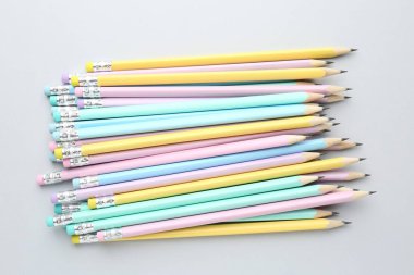 Açık gri arkaplanda silgileri olan bir sürü grafit kalem, düz konum