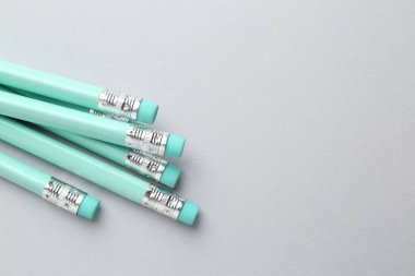 Açık gri arkaplanda silgisi olan bir sürü grafit kalem, düz bir zemin. Metin için boşluk