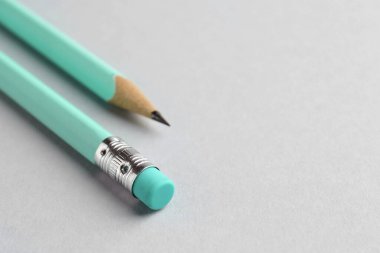 Açık gri arka planda iki grafit kalem, yakın plan. Metin için boşluk