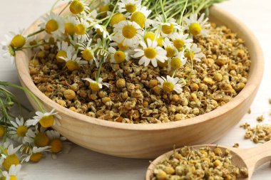 Kuru, taze papatya çiçekleri kasede ve kaşık açık ahşap masada, yakın plan