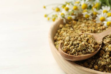 Kuru, taze papatya çiçekleri kasede ve kaşık açık tahta masada, yakın plan. Metin için boşluk