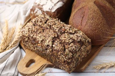 Taze ekmek somunları ve çiviler beyaz ahşap masada, yakın plan.