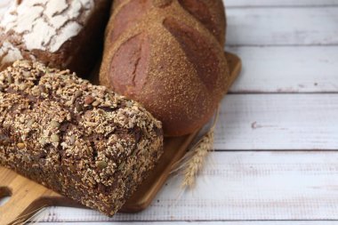 Taze ekmek somunları ve çiviler beyaz ahşap masada, yakın plan.