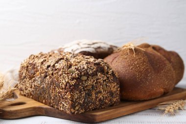 Taze ekmek somunları ve çiviler beyaz ahşap masada, yakın plan.