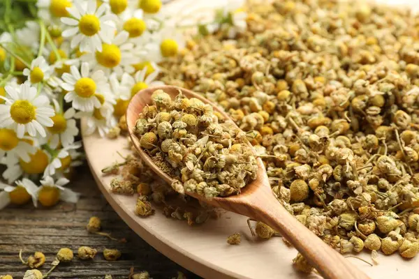 Kuru, taze papatya çiçekleri ve kaşıklar masada, yakın plan.