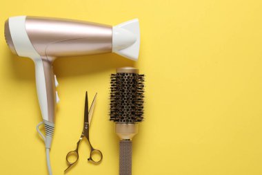 Sarı arka planda farklı saç şekillendirme araçları, düz yatış. Metin için boşluk