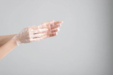 Açık gri arka planda ellerini sabunla yıkayan kadın, yakın plan. Metin için boşluk