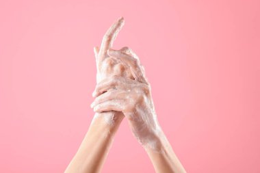 Açık pembe arka planda ellerini sabunla yıkayan kadın, yakın plan.