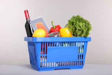 Gri arka planda farklı gıda ürünleri olan alışveriş sepeti.