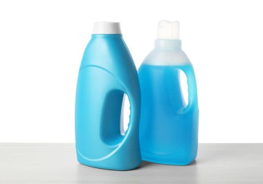 Beyaz arka plana karşı ahşap masada yumuşatıcı şişeler.