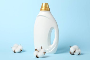 Bir şişe yumuşatıcı ve açık mavi arkaplanda pamuk çiçekleri.