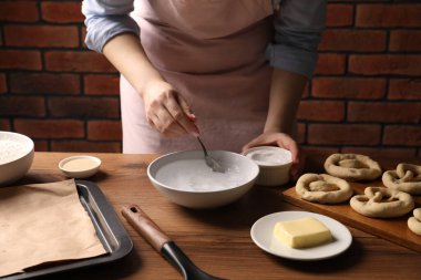 Kraker yapıyorum. Ahşap masada bir kase suya kabartma tozu ekleyen kadın, yakın plan.