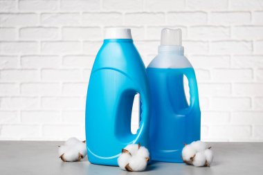 Beyaz tuğla duvara karşı gri masada yumuşatıcı ve pamuk çiçekleri.