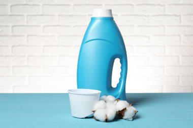 Beyaz tuğla duvara karşı açık mavi masada yumuşatıcı ve pamuk çiçekleri.