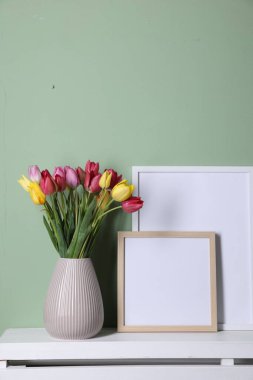 Renkli duvarın yanındaki masada bir buket güzel lale ve çerçeve. Metin için boşluk