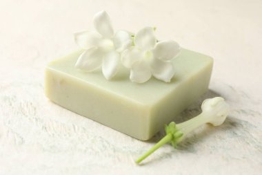 Bir kalıp sabun ve yasemin çiçekleri ışık masasında, yakın plan.