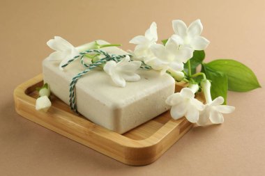 Açık kahverengi arka planda sabun ve yasemin çiçekleri, yakın plan.