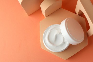Turuncu arka planda kavanozda nemlendirici vücut kremi sunumu, üst manzara. Metin için boşluk