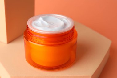 Turuncu arka plandaki kavanozda nemlendirici vücut kremi sunumu, yakın plan.