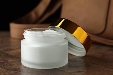 Bir kavanoz nemlendirici vücut kremi ve deri çanta ahşap masada, yakın plan.