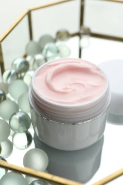 Beyaz masadaki nemlendirici krem ve cam tepsi, yakın plan.
