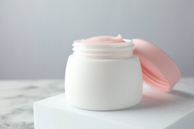 Beyaz mermer masanın üzerinde bir kavanoz nemlendirici vücut kremi, yakın plan.