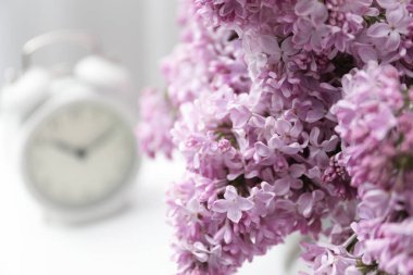 Güzel leylak çiçekleri ve alarmlı saat kapalı bir masada, yakın plan. Metin için boşluk