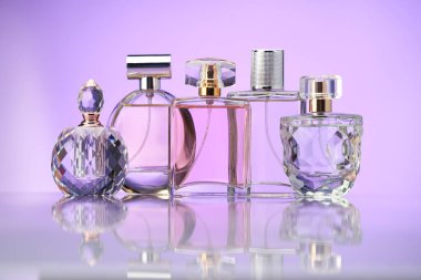 Ayna yüzeyinde mor arka planda parfüm şişeleri