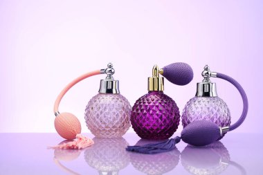 Ayna yüzeyinde soluk menekşe eğimli arka planda parfüm şişeleri