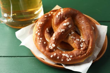 Lezzetli krakerler ve yeşil ahşap masada bir bardak bira, yakın plan.